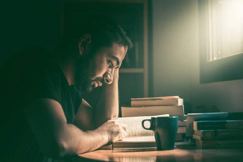 Fotografía de un joven estudiando sus libros en su cuarto