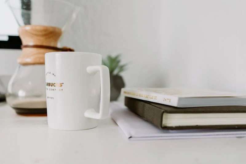 Fotografía de una taza de café acompañada de unos libros 