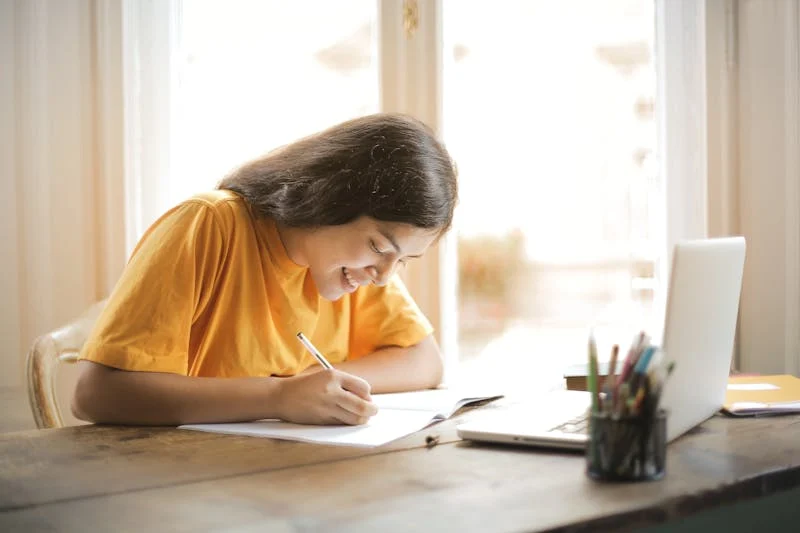 Fotografía de estudiante escribiendo en su escritorio