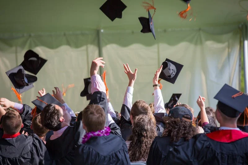 Imagen donde se muestra a alumnos de universidad graduándose y tirando sus birretes 