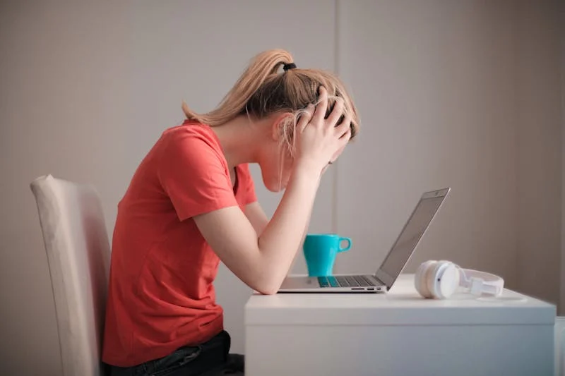 estudiante que revisa sus apuntes en su laptop mientras toma una taza de cafe