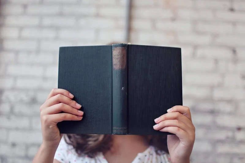 Fotografía de mujer estudiante con un libro en su cabeza